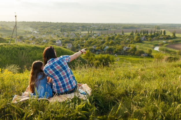 Little cute girl with her mother sitting at sunset