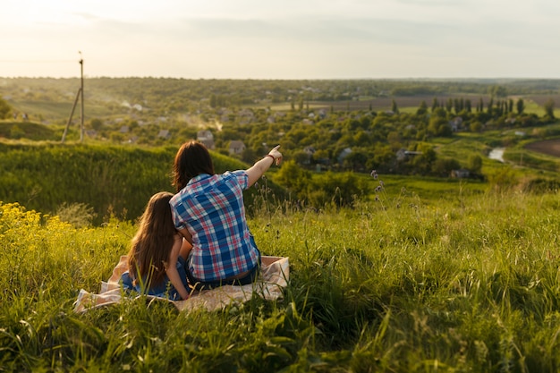 Little cute girl with her mother sitting at sunset