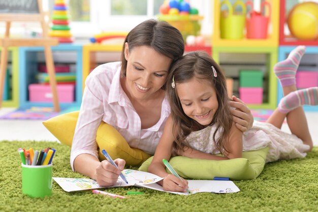 Little cute girl with mother drawing at home