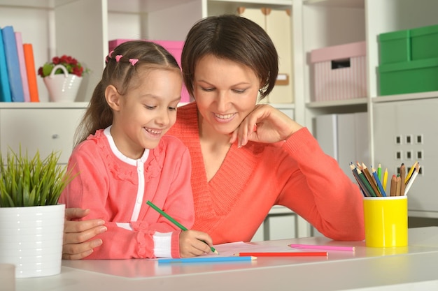 Little cute girl with mother drawing picture at home