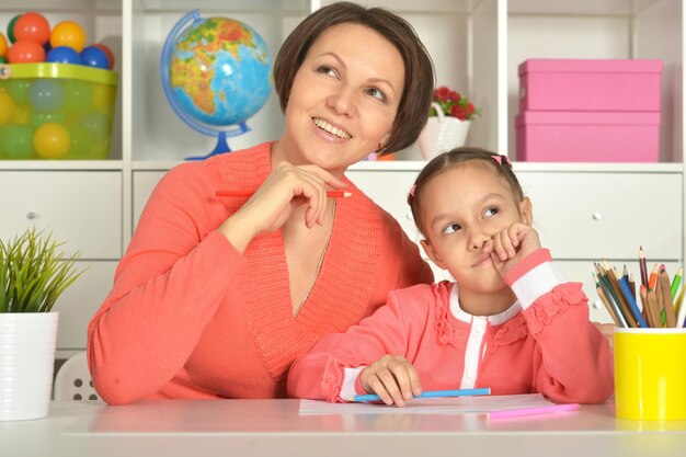 Little cute girl with mother drawing picture at home