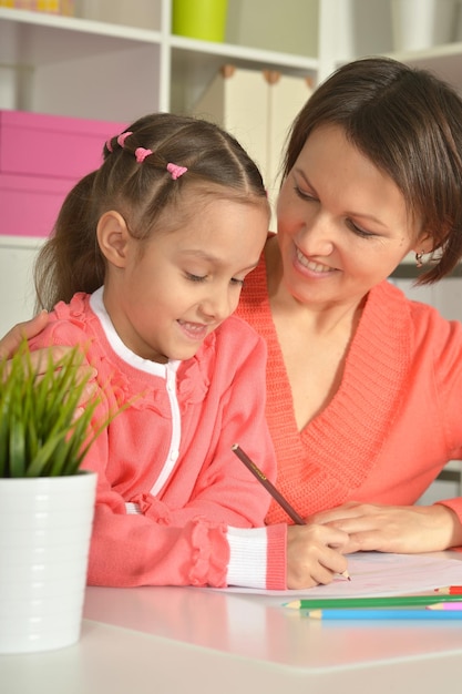 Little cute girl with mother drawing picture at home