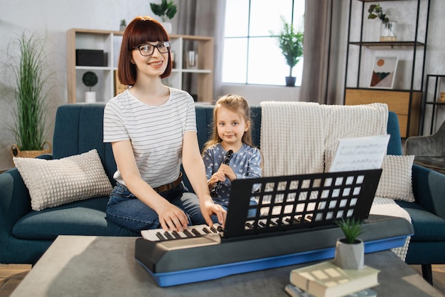 Little cute girl with music teacher having lesson at flute at school of music