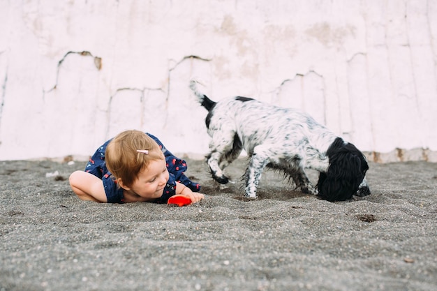 Bambina carina con cocker spaniel russo che gioca sulla spiaggia in riva al mare