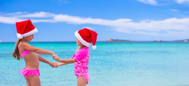 Little cute girls in Santa hats during summer vacation