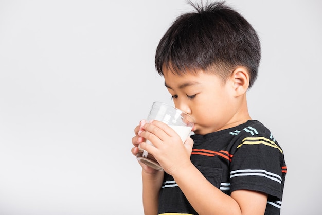 Little cute kid boy 5 years old smile holding milk glass he drinking white milk