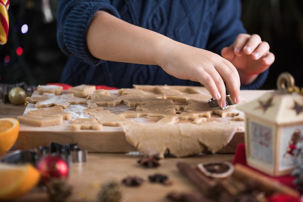 小さなかわいい男の子は、新年のキッチンでクリスマスのジンジャーブレッドクッキーを作ります。