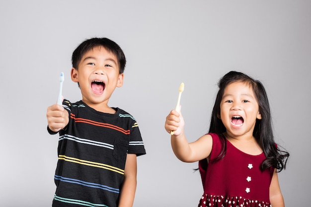 작은 귀여운 꼬마 소년은 이를 닦고 미소를 짓습니다.