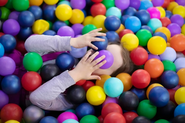 Foto piccola ragazza sveglia del bambino gioca con le palle di plastica nel centro giochi per bambini