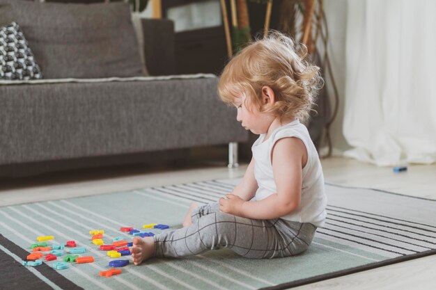 Little cute toddler playing with toy letters sitting on the floor