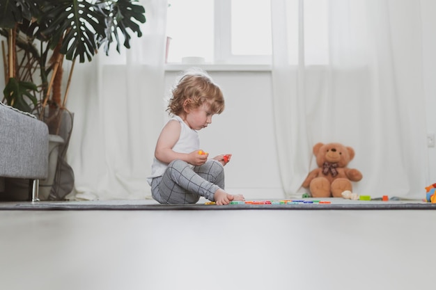 Little cute toddler playing with toy letters sitting on the floor