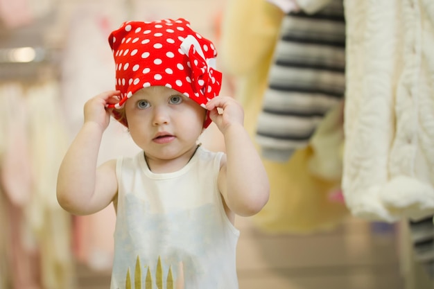 Foto bambina carina anni in un cappello rosso a pois al negozio di abbigliamento per bambini