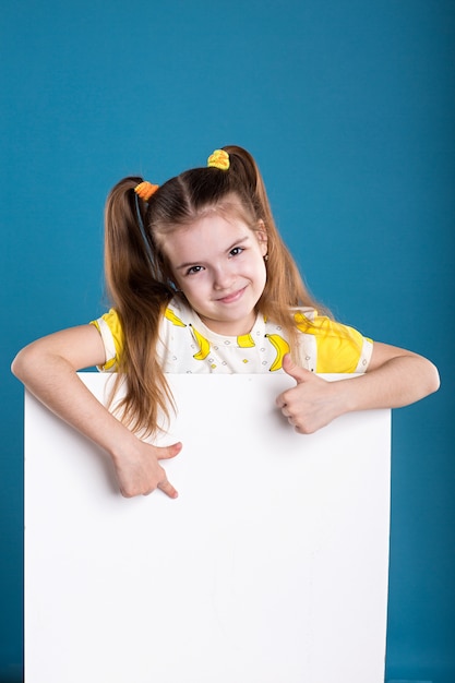 Little dark hair girl in banana T-Shirt poses with white board