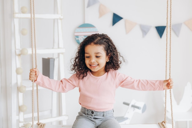 A little darkskinned girl rides on a swing kids room interior design