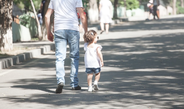Маленькая дочь и отец гуляют в парке