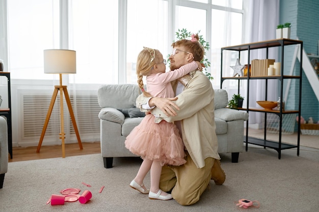 Little daughter hugging and kissing happy smiling father over
home living room interior, cute family portrait