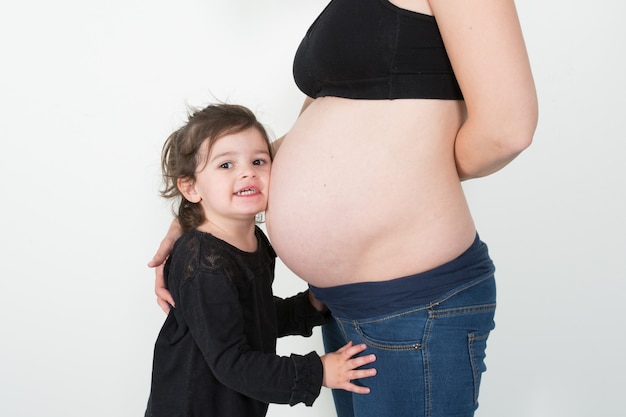 Photo little daughter listening to mother pregnant belly