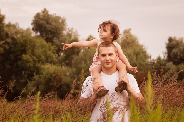 little daughter sits on father’s shoulders
