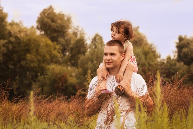 little daughter sits on father’s shoulders