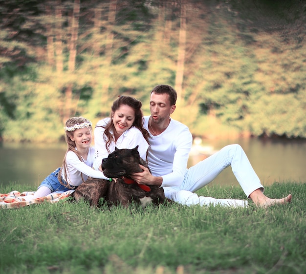 ,little daughter and their dog on a picnic by the river.the photo has a space for your text