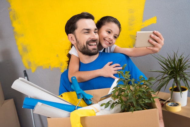 Little daughter using smartphone does selfie with her father