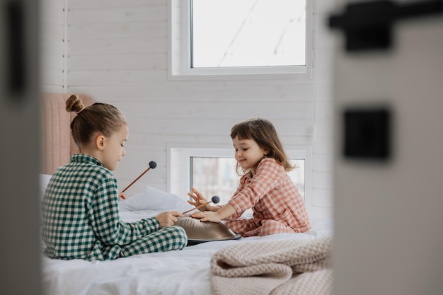 little daughters play in the bedroom on their parents bed playing the glucophone