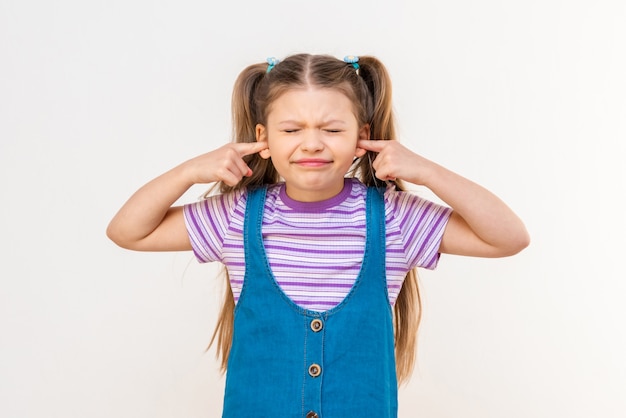 A little dissatisfied girl covers her ears from the loud noise.