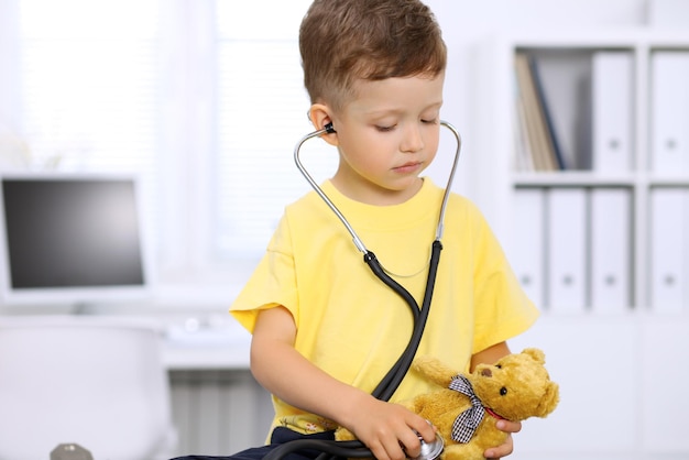 Foto piccolo medico che esamina un paziente dell'orso del giocattolo dallo stetoscopio