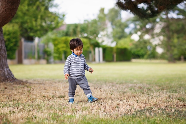 Piccolo neonato bello orientale che gioca all'aperto nel parco