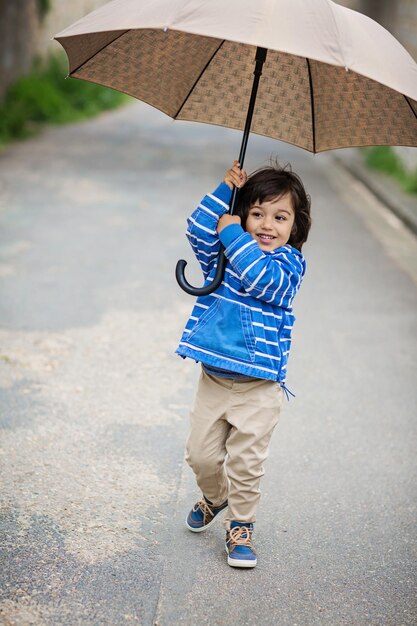 Little eastern handsome baby boy playing with umbrella outdoor