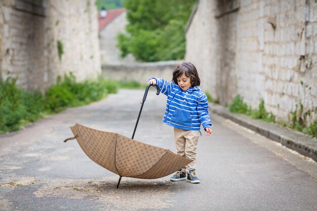 Little eastern handsome baby boy playing with umbrella outdoor