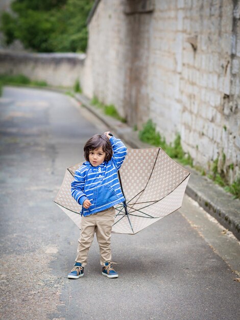 Little eastern handsome baby boy playing with umbrella outdoor