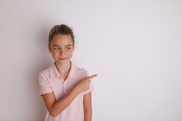 Little emotional teen girl in pink shirts 11 12 years old on an isolated white background Children39s studio portrait Place text to copy space for inscription advertising children39s goods