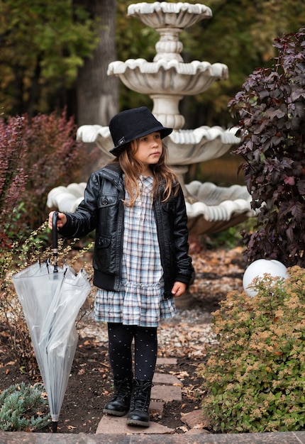 秋の公園で傘と革のジャケットの小さなヨーロッパの女の子