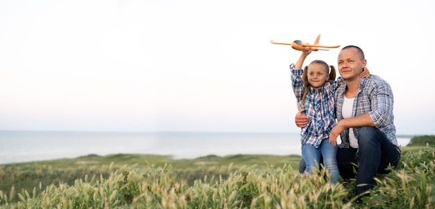 Piccolo papà e figlia di famiglia insieme all'aperto in estate giovane con una ragazza in ginocchio guardando il cielo al tramonto festa del papà concetto di vacanza con bambini banner