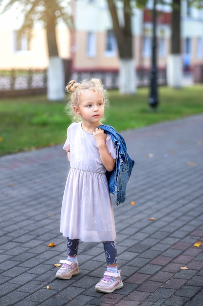 Little fashionable girl walks on the path in the park