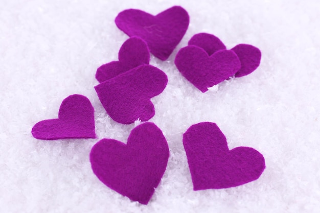 Little felt hearts on snowy background