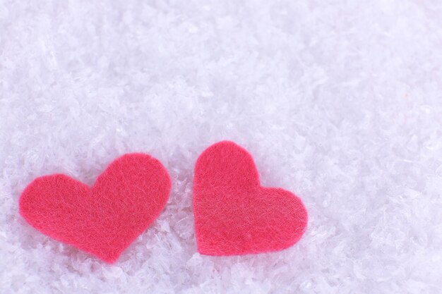 Little felt hearts on snowy background