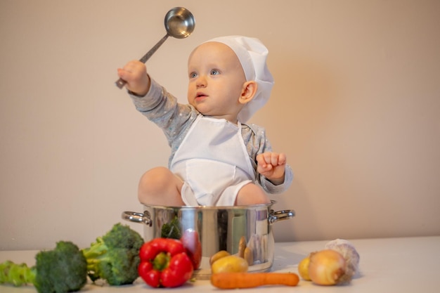 Little female chef preparing vegetable soup in kitchen