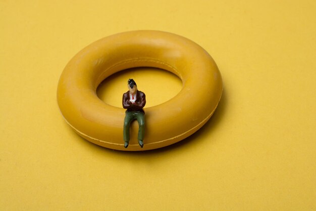 Little figurine man sitting on a life preserver