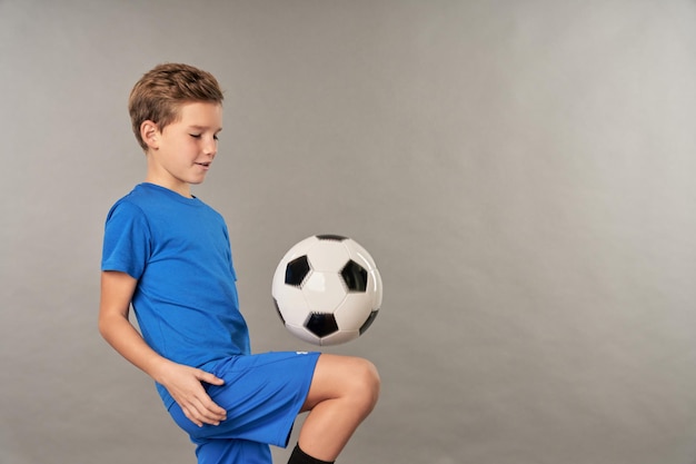 Foto piccolo giocatore di football che fa trucchi con il pallone da calcio