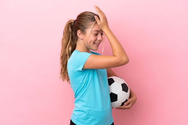 ピンクの背景に分離された小さなサッカー選手の女の子は何かを実現し、解決策を意図しています