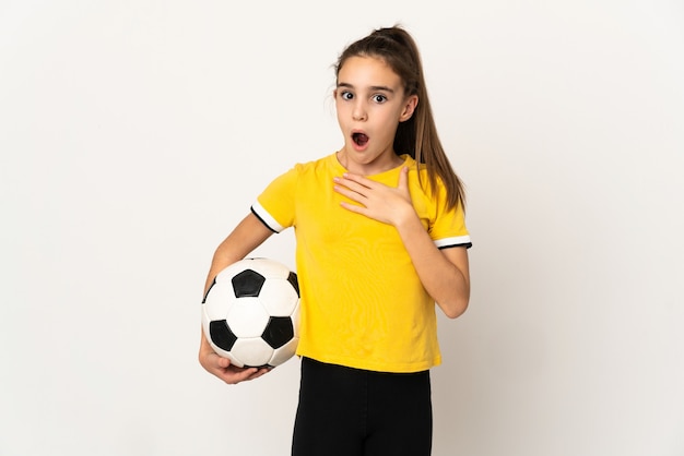 白い背景で隔離の小さなサッカー選手の女の子は、右を見ながら驚いてショックを受けました