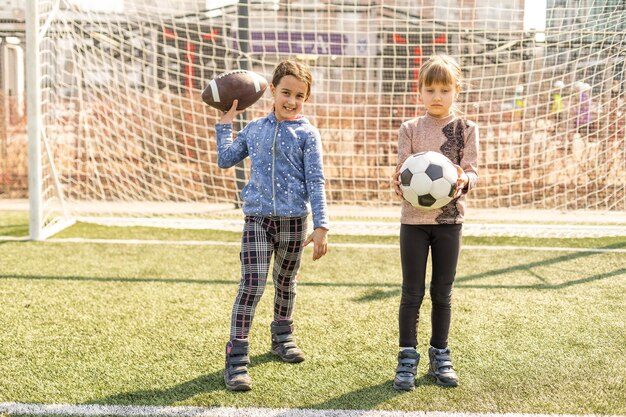 Photo little football team: toddler girls with soccer ball at football field.