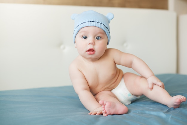그의 머리에 귀를 가진 귀여운 모자와 함께 웃고 큰 파란 눈을 가진 작은 재미있는 아기