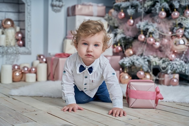 Little funny baby next to the Christmas tree.
