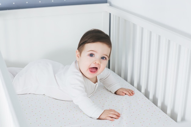 Little funny boy lying in baby bed and laughing