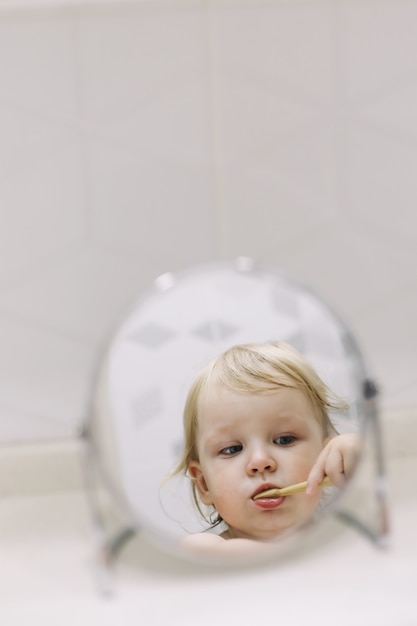 Photo little funny girl brushing her teeth in the bathroom