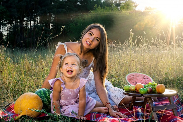 Little funny girl with her mother on a summer picnic