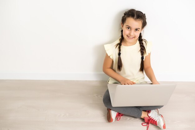 Little funny girl with laptop on white background.